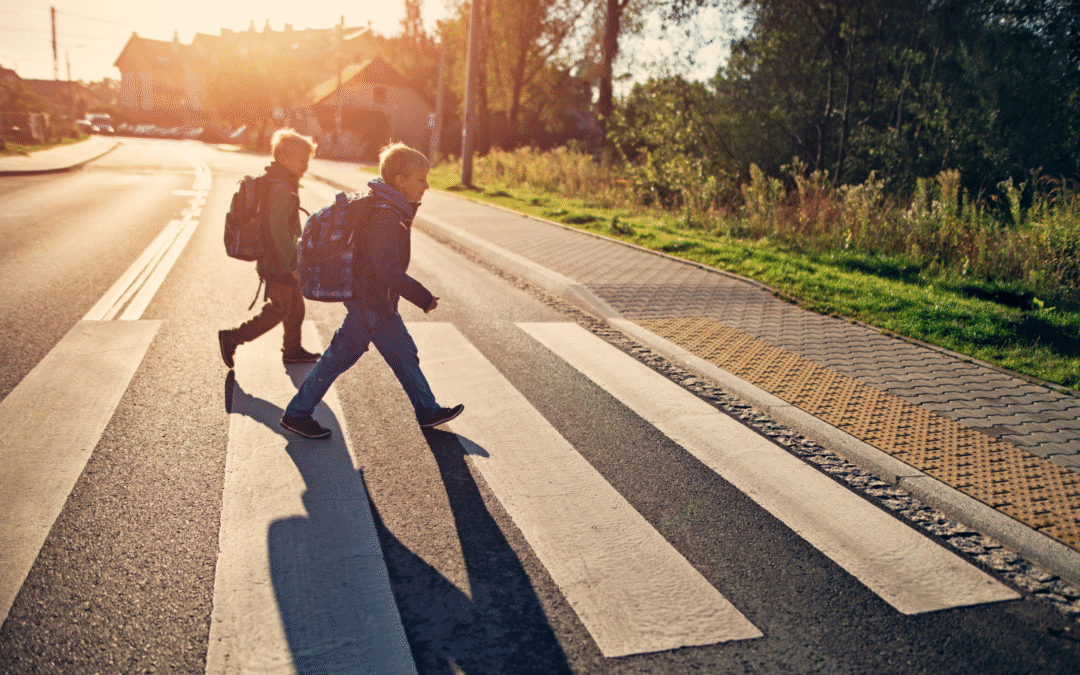 two kids crossing a crosswalk with backpacks on